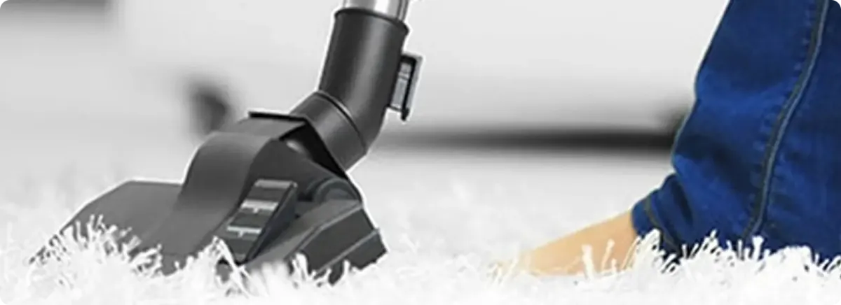 Close-up of a professional vacuuming a white carpet in Mooseheart.